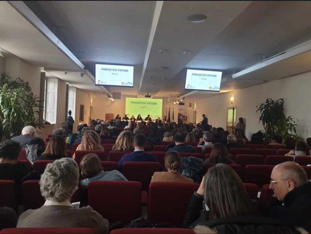 The full conference hall at Palazzo Reale with Parastoo Fatemi's name on three screens